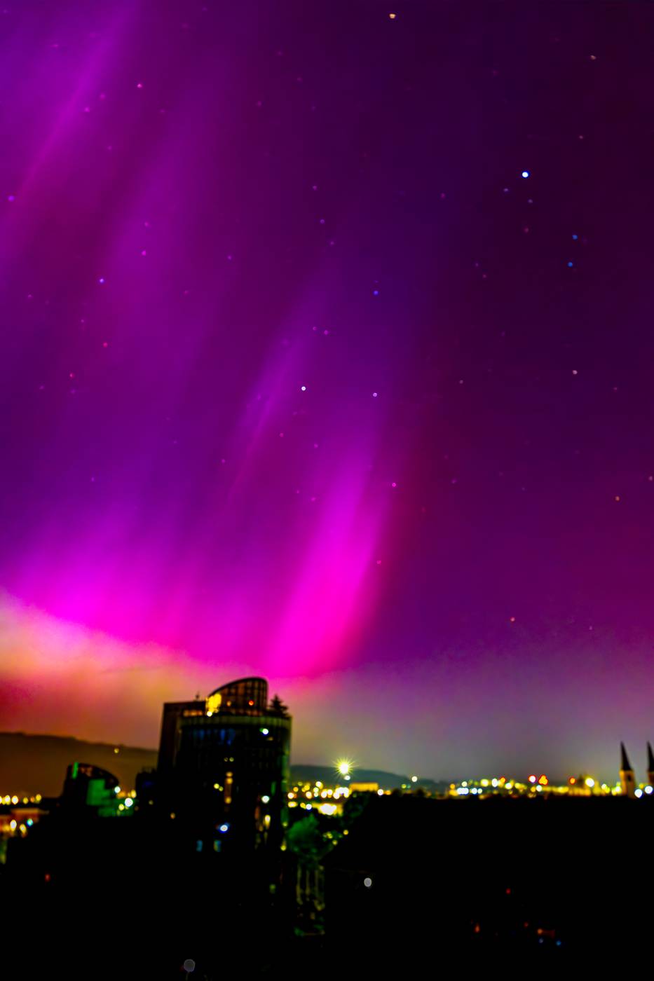 Violettes Polarlicht über einer Stadt bei Nacht